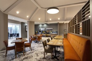 Un restaurant moderne doté d’un long comptoir, de plusieurs tables et d’un espace détente avec un banc.