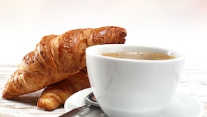 Un croissant y una taza de café sobre un plato blanco.