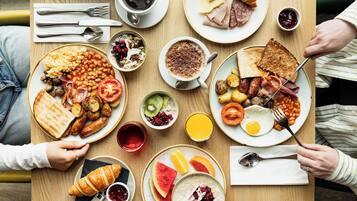 Un desayuno con diversos platos, incluyendo tostadas, huevos, salchichas y un croissant.
