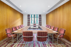 Ein Konferenzraum mit einem langen Tisch, gemusterten Stühlen und Blick durch große Fenster.