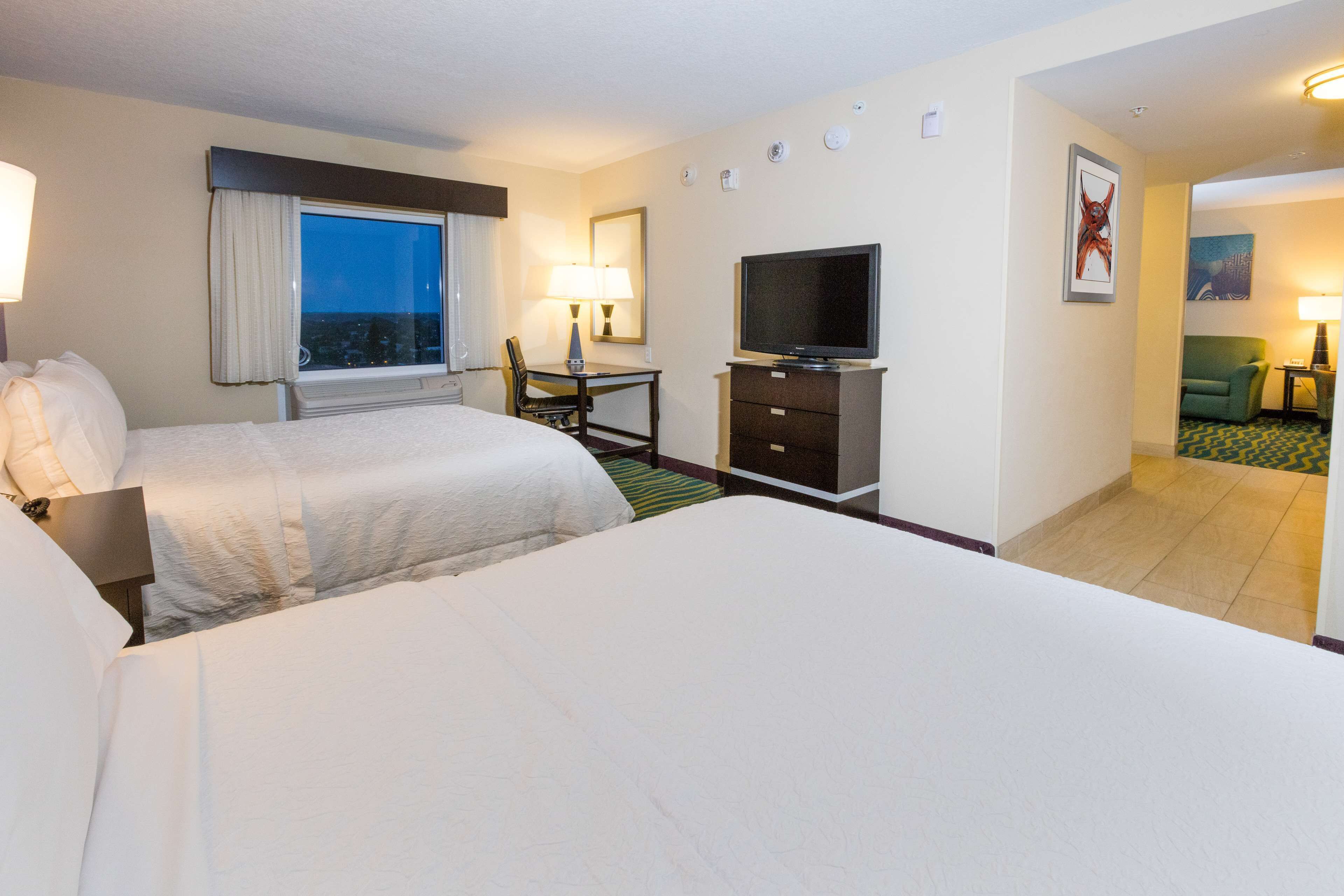 A hotel room with two beds, a TV, a desk, and a chair.