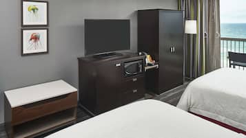 Habitación de hotel con dos camas, televisión, escritorio y armario.