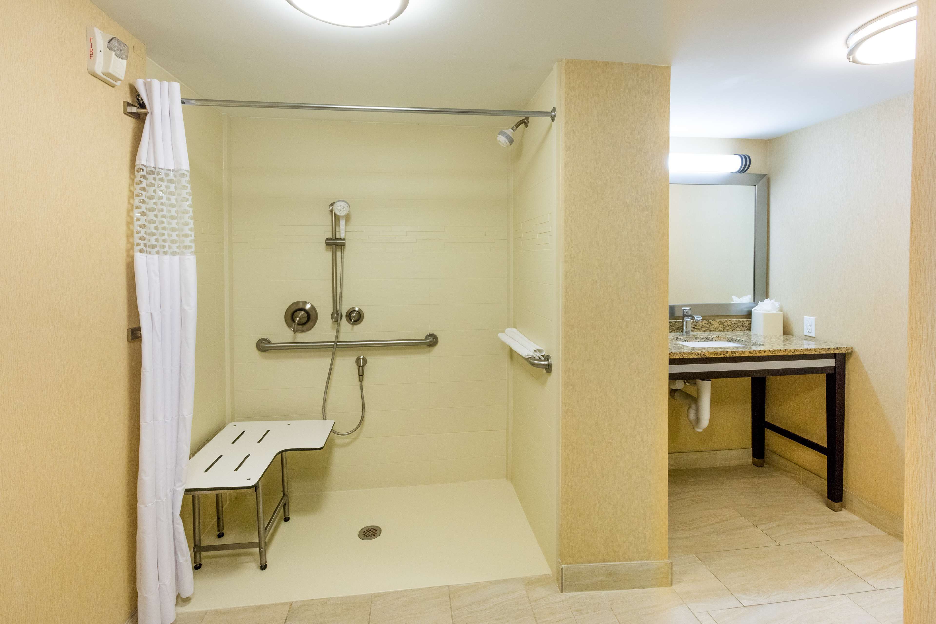 A handicap-accessible shower with a grab bar, a bench, and a toilet.