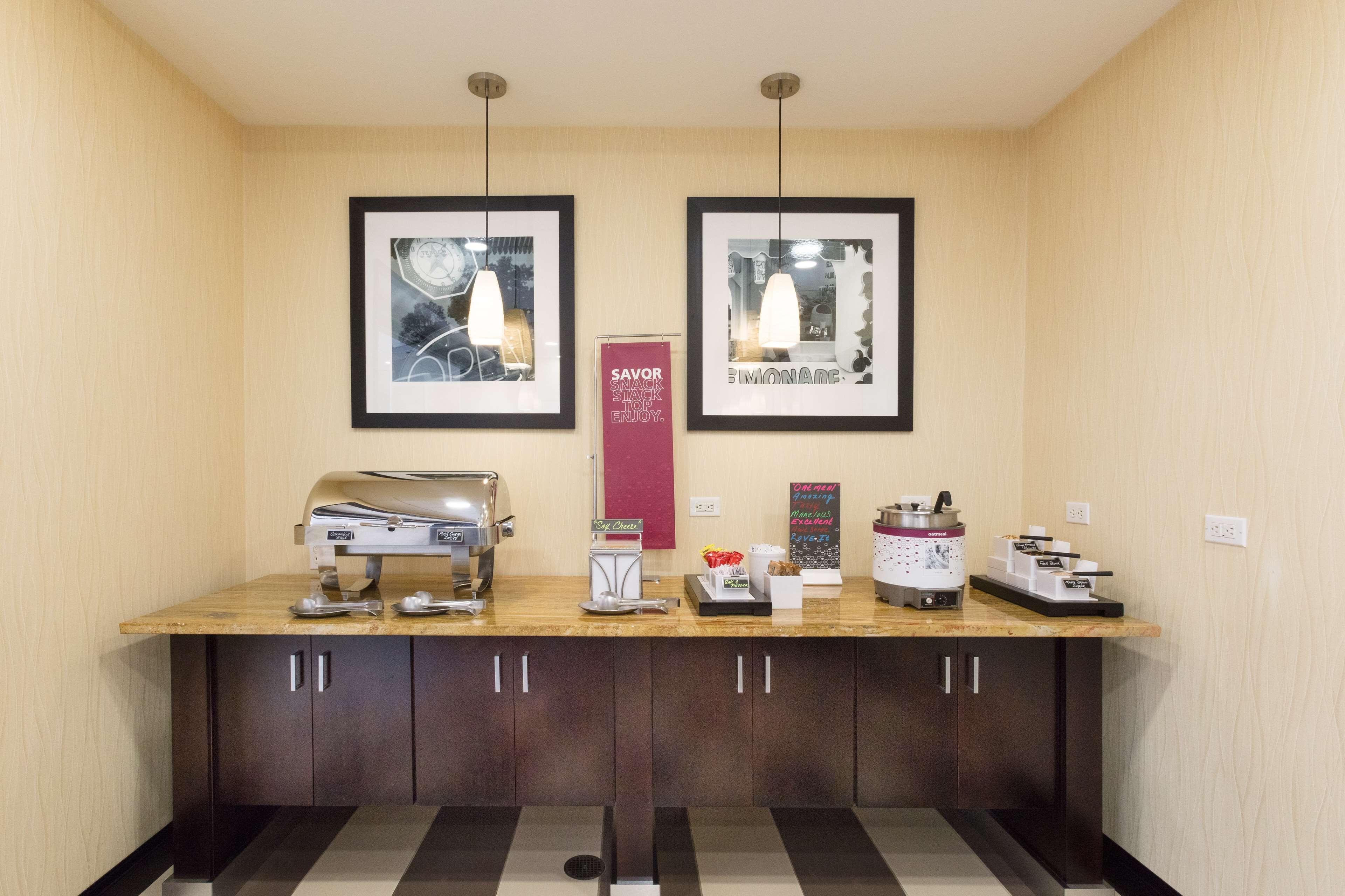 A reception area with a counter, framed artwork, a coffee machine, and a sign promoting a snack station.