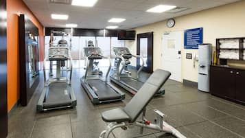 A gym with treadmills, a bench press, and a water dispenser.