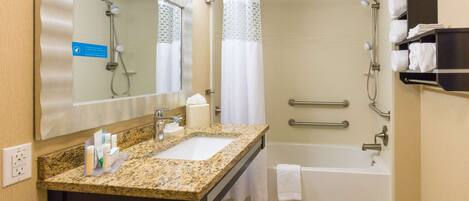 A bathroom with a granite countertop sink, a mirror, a shower with a glass door, and a bathtub.