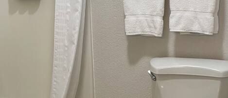 A bathroom with a bathtub, toilet, and a trash bin.