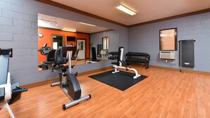 Un gimnasio con equipo de ejercicio, una colchoneta negra y un espejo.