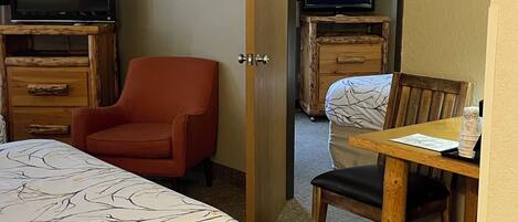 A hotel room with a bed, a desk, a chair, a television, and a mirror.
