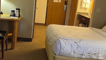 Una habitación de hotel con cama, escritorio, silla y baño.