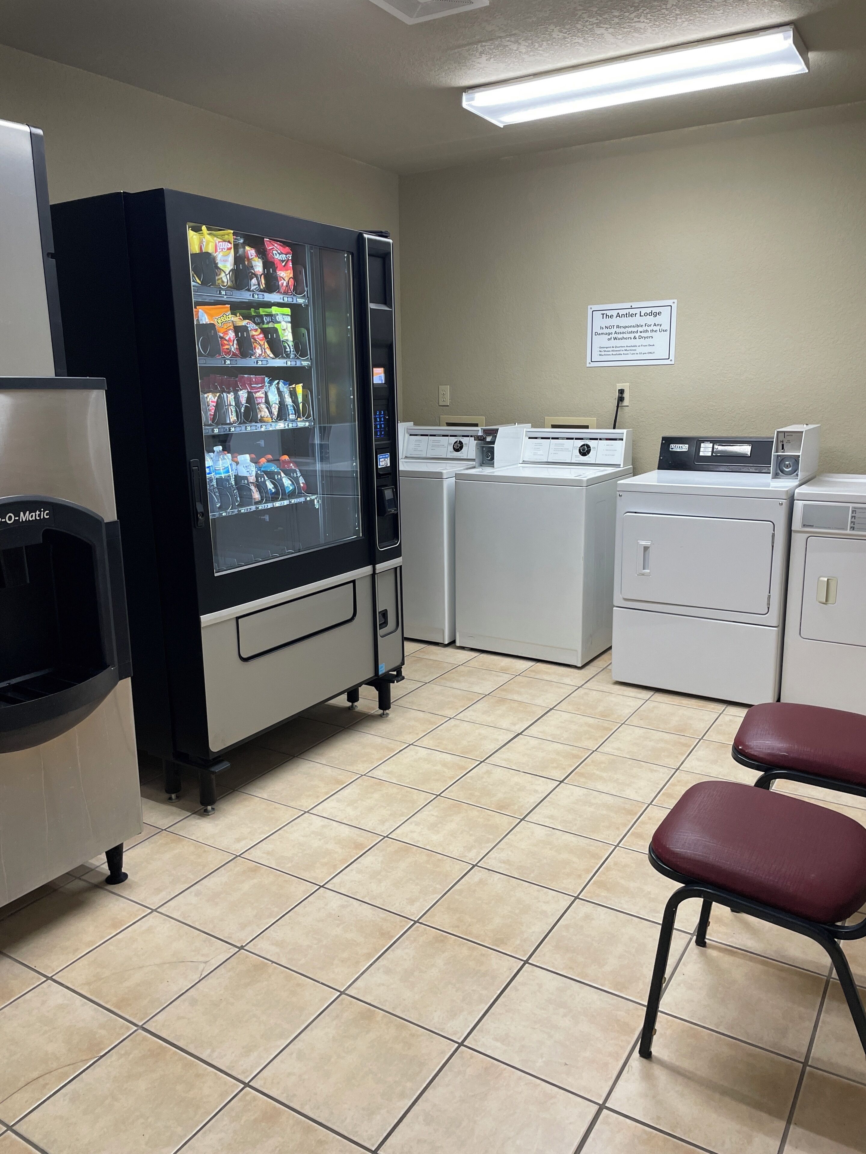 A laundry facility with a vending machine, washers, dryers, and a sign indicating it is not for use with washers and dryers.