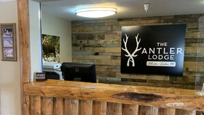 Una recepción con diseño de madera, un cartel que dice 'The Antler Lodge' en Yellowstone - Gardiner Mt., y un letrero que indica 'No se admiten mascotas'.