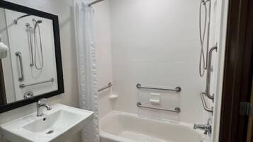 A modern bathroom with a white sink, mirror, and bathtub.