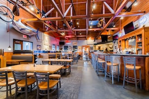 A restaurant with wooden interiors, tables, chairs, and a bar area.