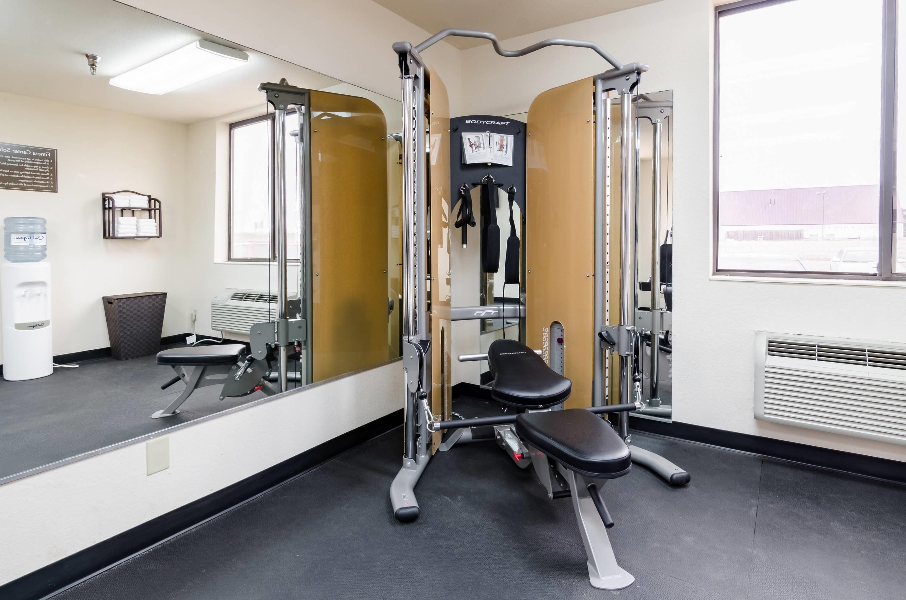 A gym with a mirrored wall, a bench, and a squat rack.
