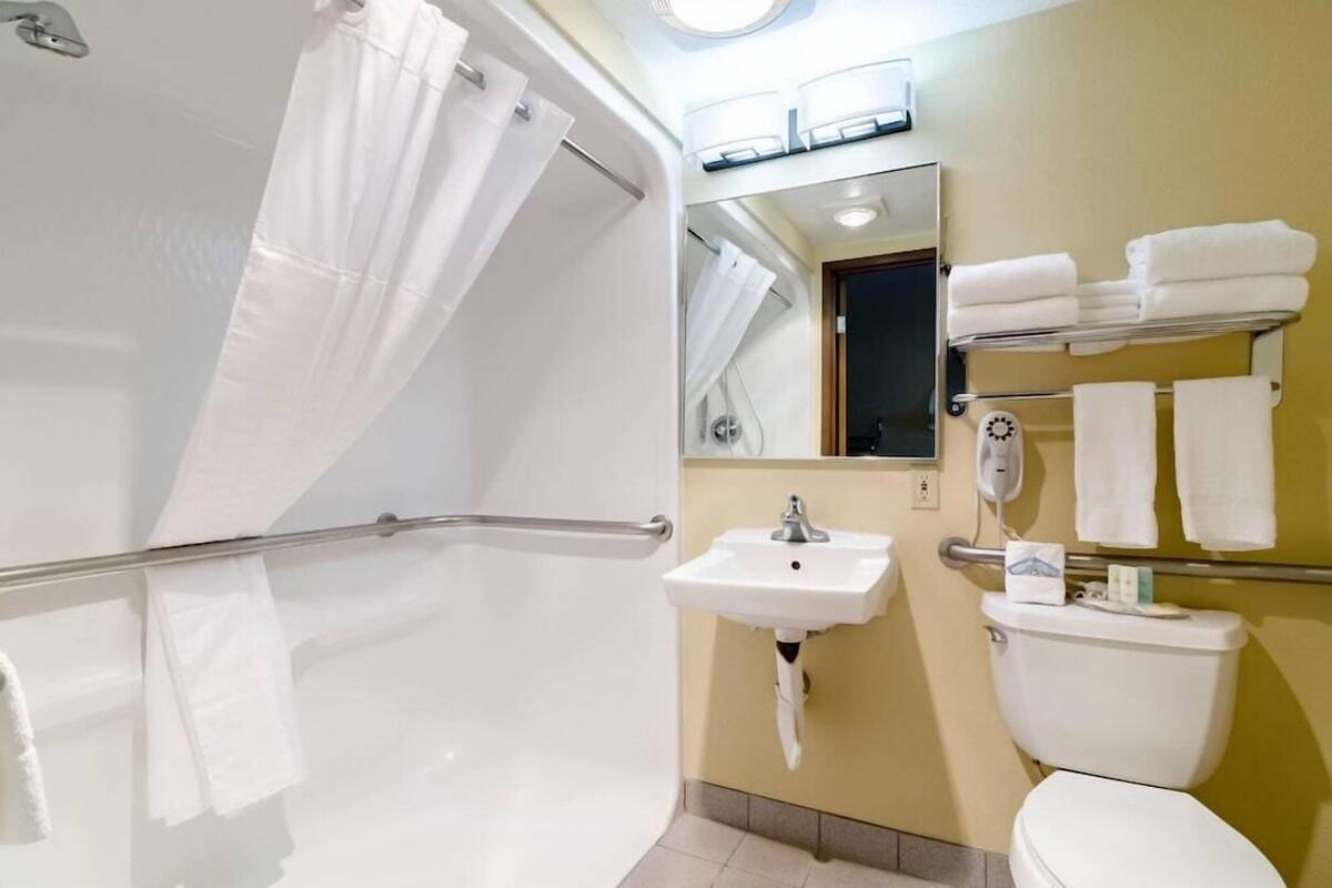 A bathroom with a shower, sink, toilet, and towel rack.