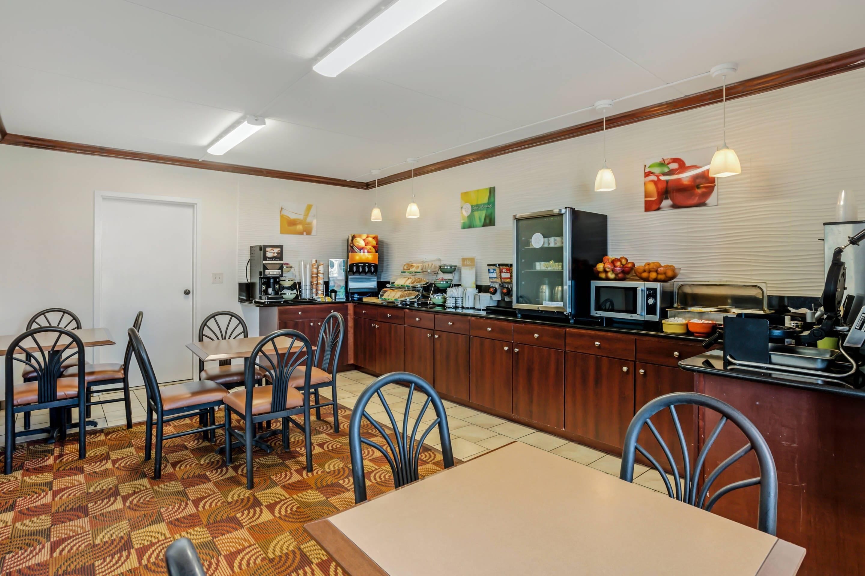 A dining area with a long counter, chairs, and a table. There are various food items and appliances on the counter.