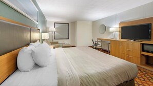 A hotel room with a large bed, a desk, a television, and a mirror.