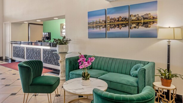 A lobby with a green sofa, a round table, and a cityscape painting.