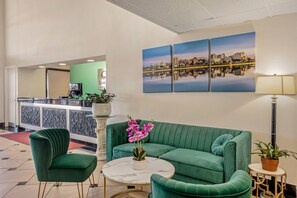 A lobby with a green sofa, a round table, and a cityscape painting.