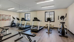 A gym with treadmills, elliptical machines, and a bench.