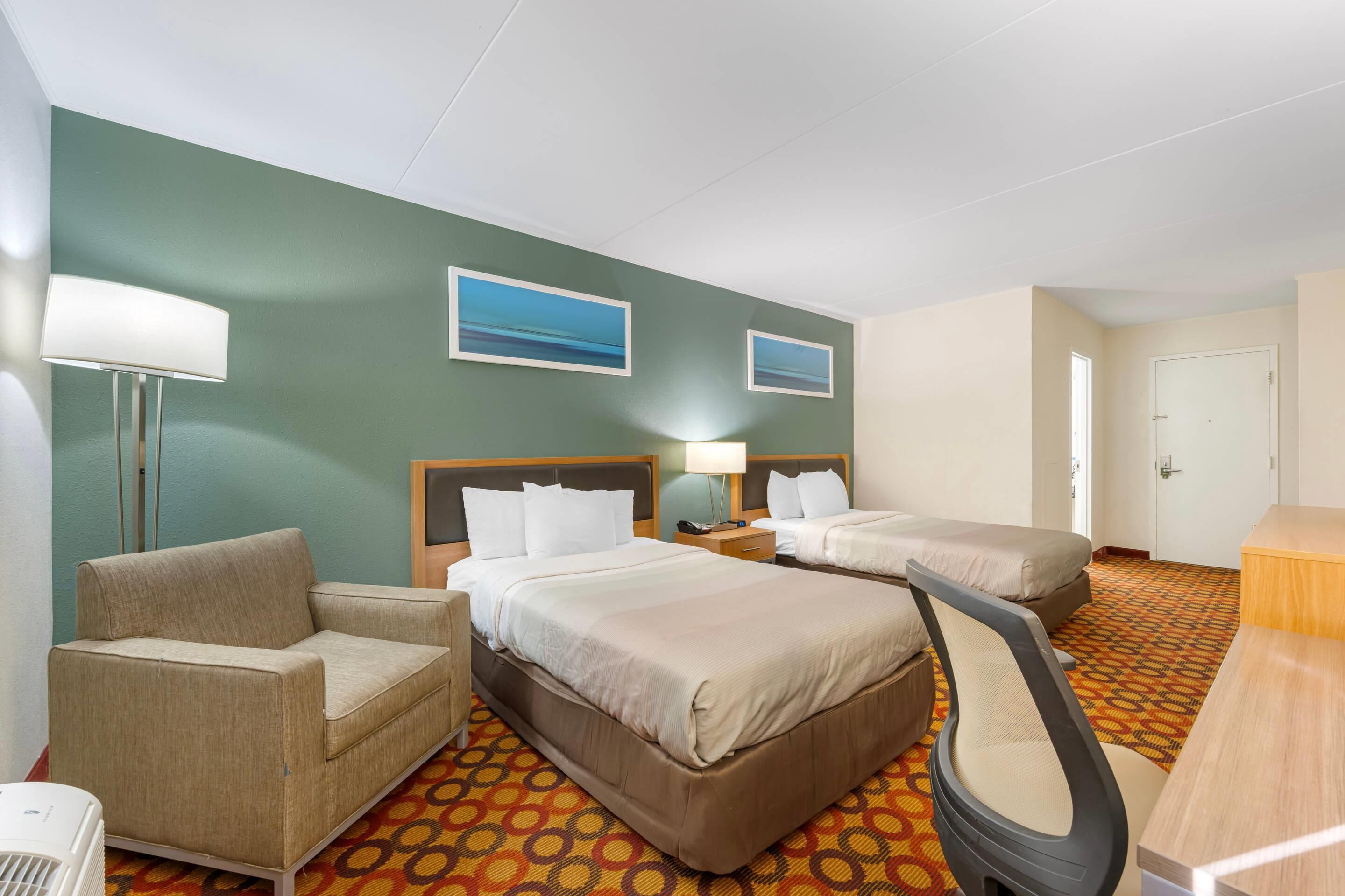 Una habitación de hotel con dos camas, un sofá, un escritorio y una silla.