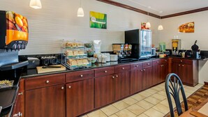 A kitchen with a coffee maker, toaster, and fruit display.
