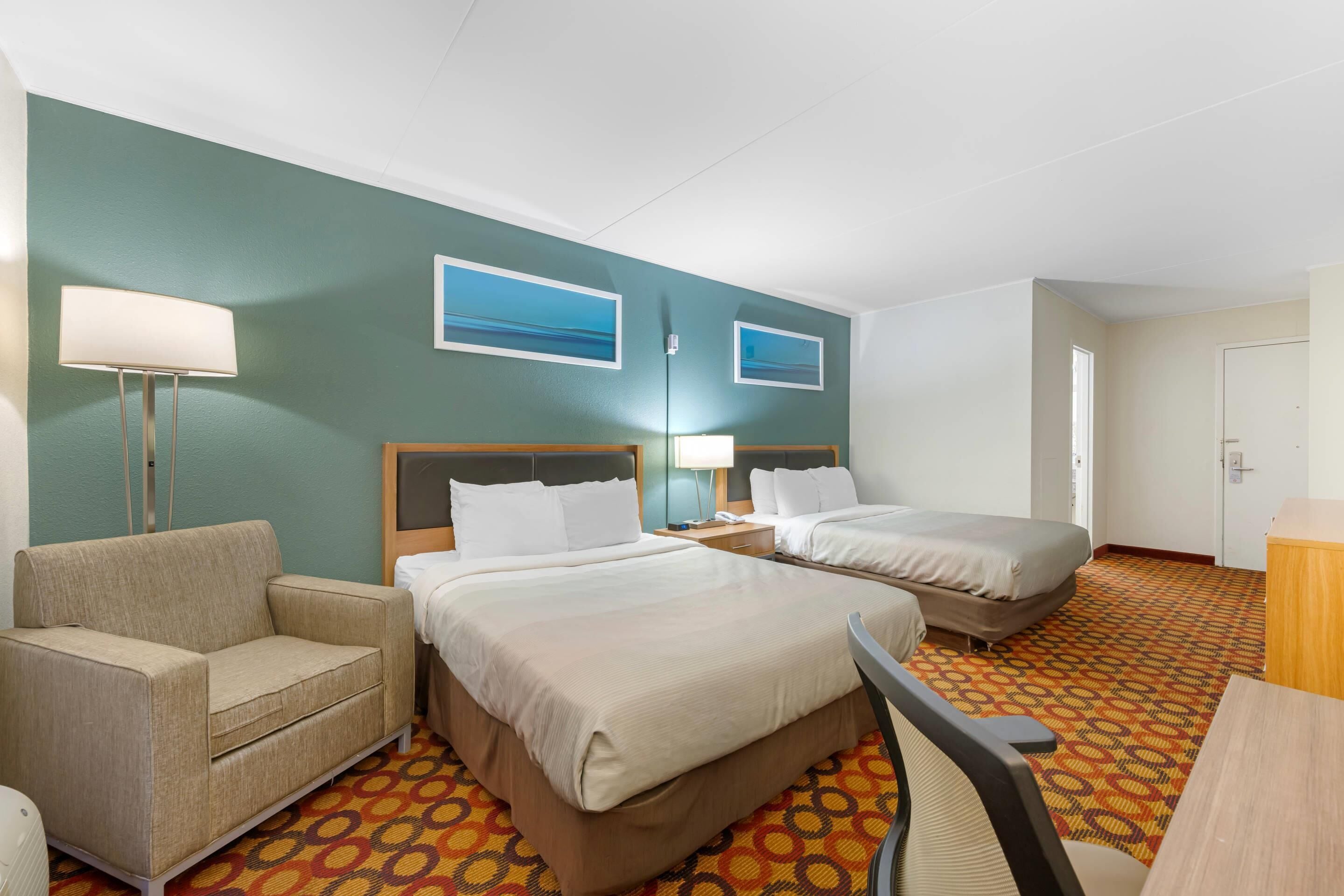 Habitación de hotel con dos camas, un sofá, un escritorio y una lámpara.