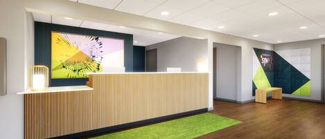 A modern reception area with a wooden reception desk, a green artificial grass rug, and a large abstract wall art piece.