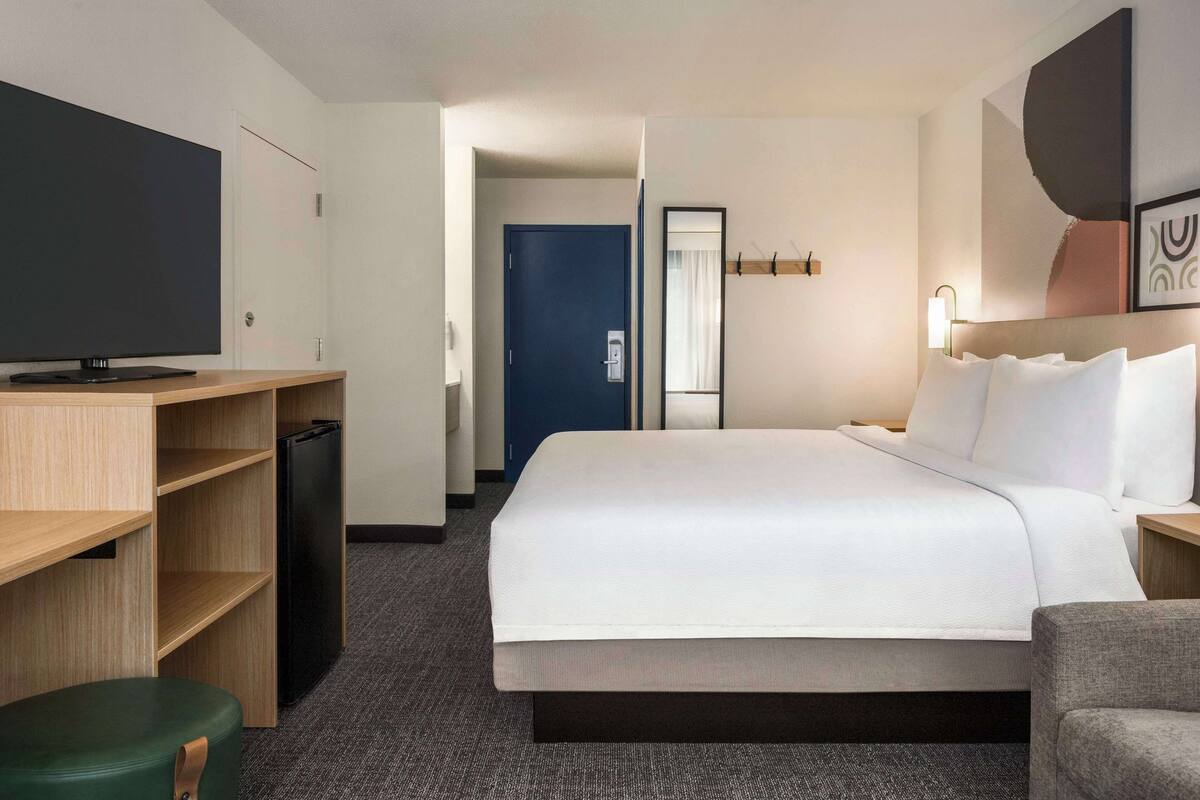 A hotel room with a bed, a television, a desk, and a wardrobe.