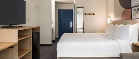 Una camera d'albergo con un letto, una televisione, una scrivania e un armadio.