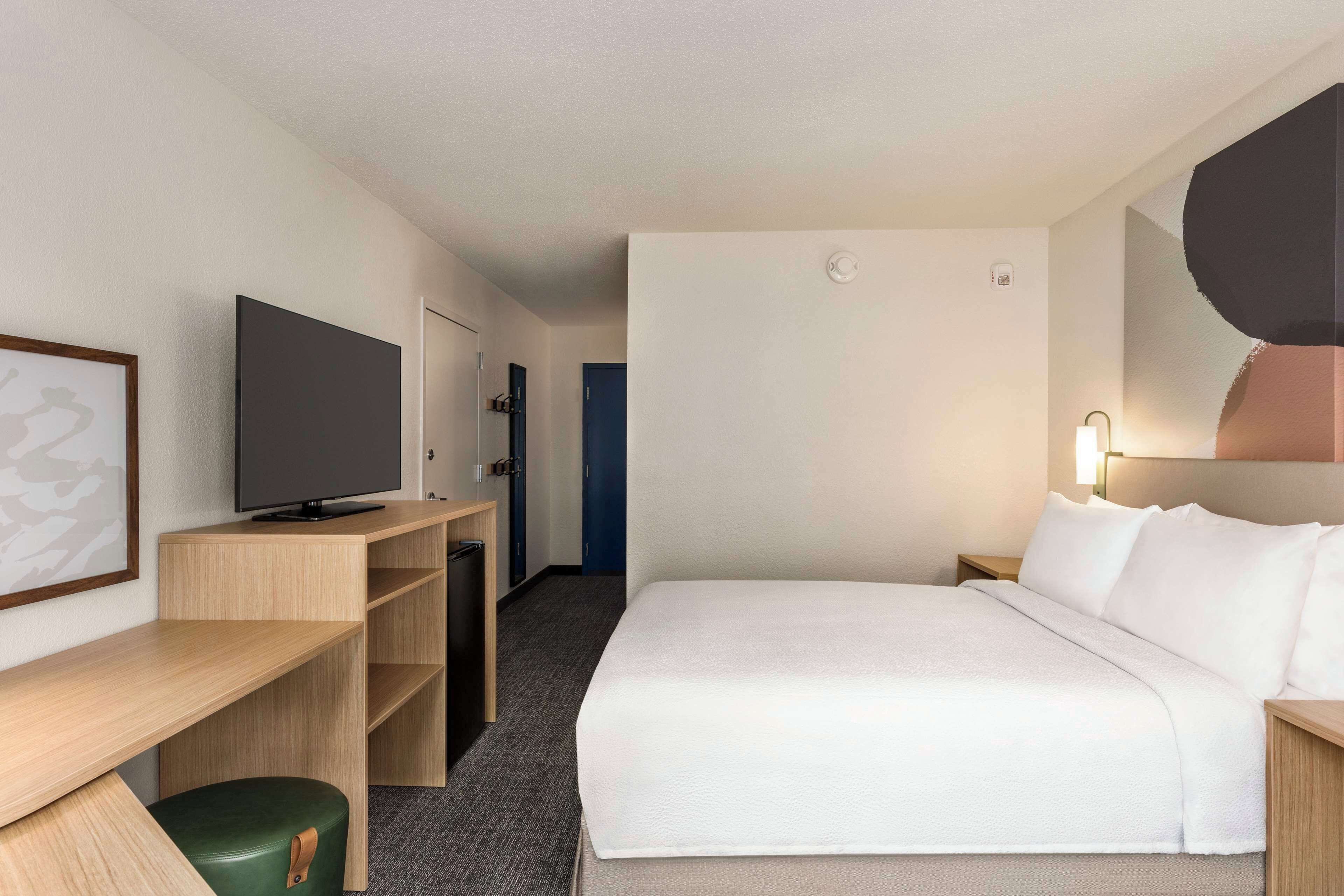 Een hotelkamer met een bed, een bureau, een televisie en een stoel.