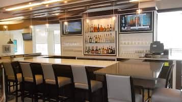 A bar area with a long counter, multiple seating options, and a television screen.