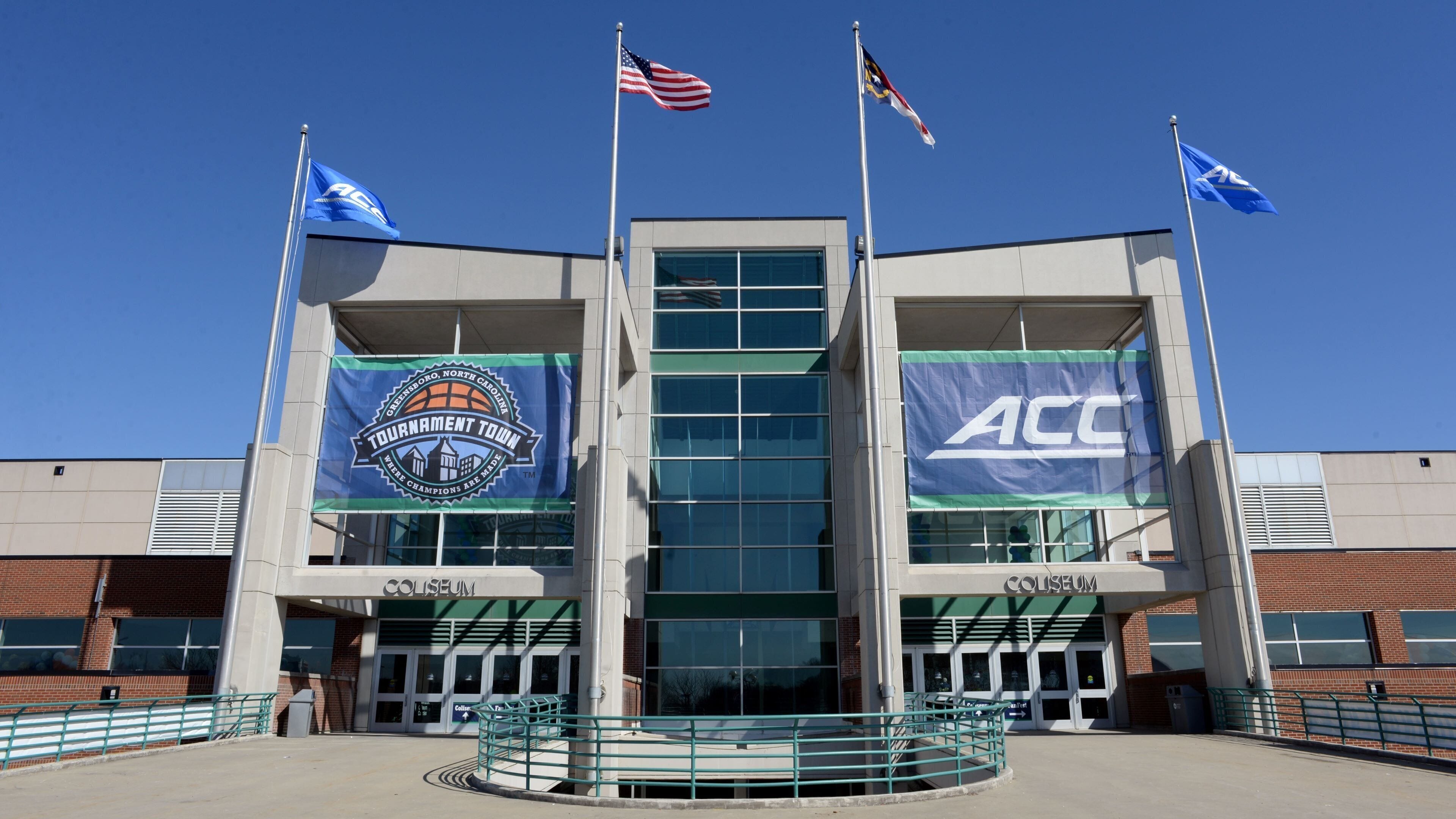 A sports arena with multiple flags, including the ACC logo, and banners for the North Carolina Tournament Town.