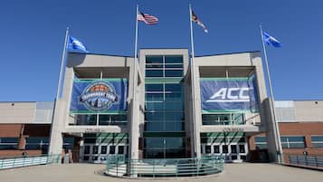 A sports arena with multiple flags, including the ACC logo, and banners for the North Carolina Tournament Town.