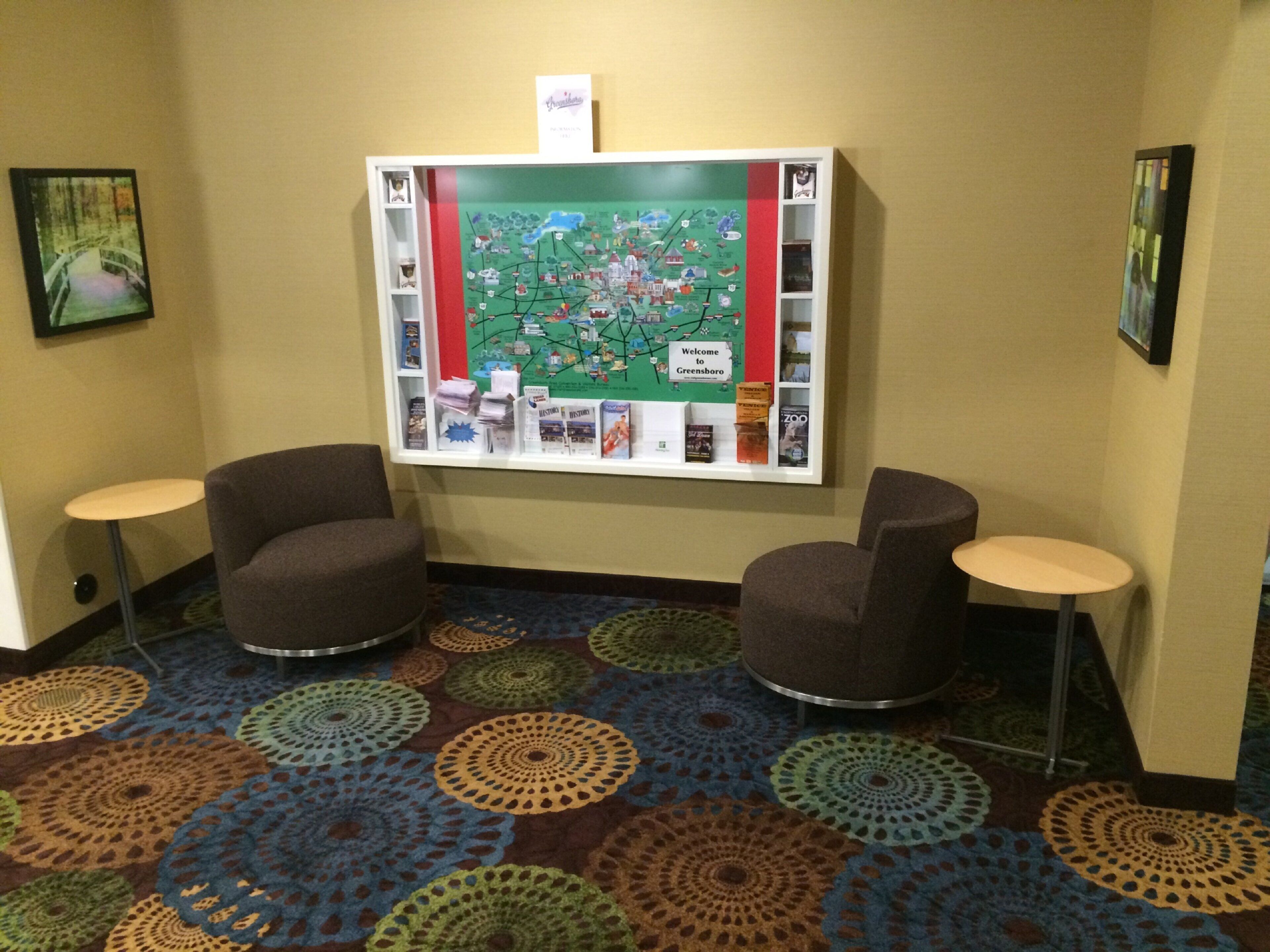 A lobby with a map display, two armchairs, and a patterned carpet.