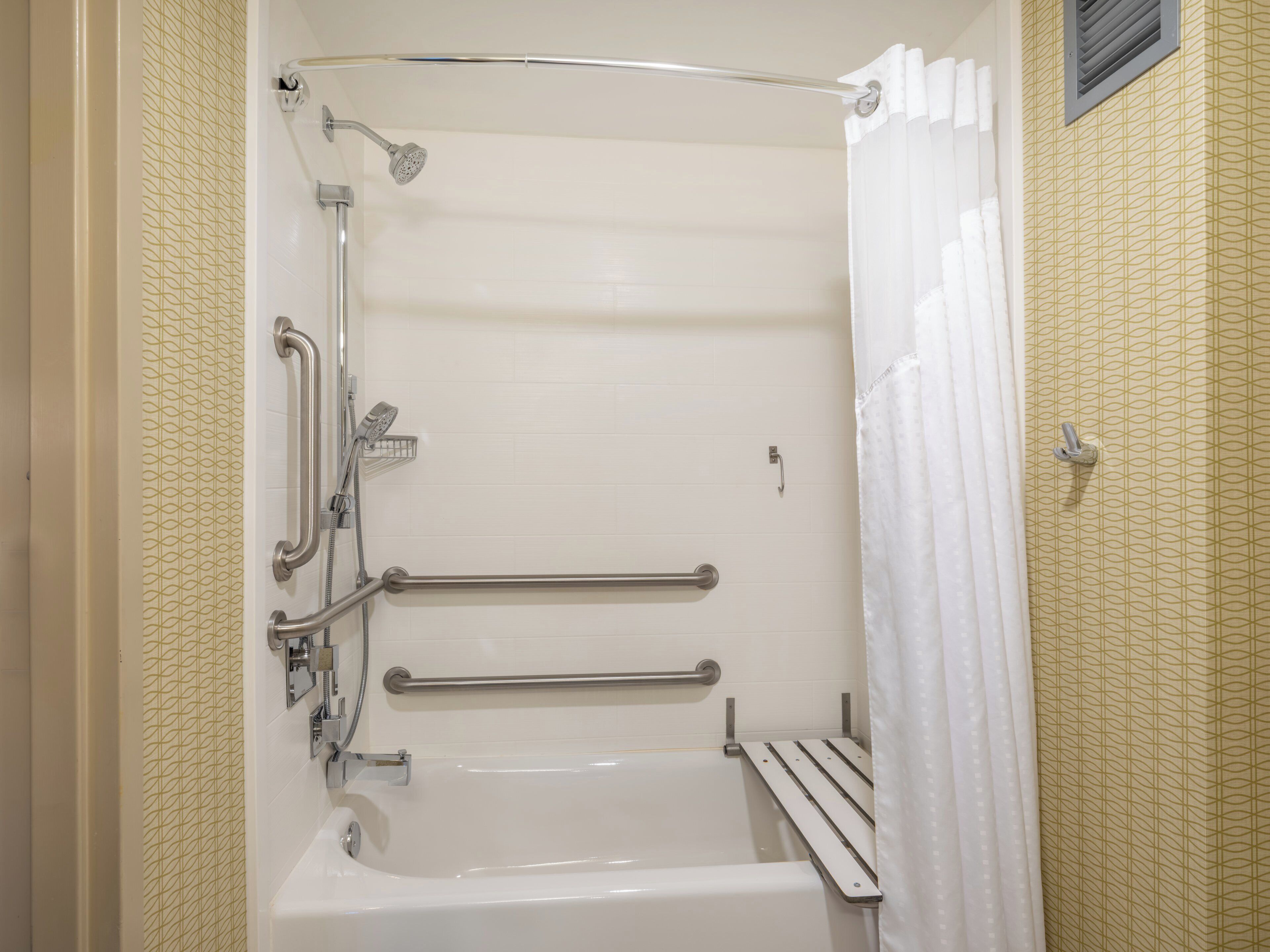 A walk-in shower with a bathtub, grab bars, and a showerhead.