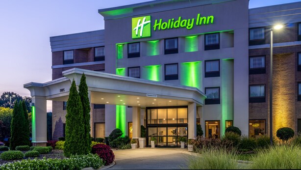 A Holiday Inn hotel with a modern design, featuring a prominent entrance and a well-lit facade. - Holiday Inn Greensboro Coliseum by IHG (Greensboro)