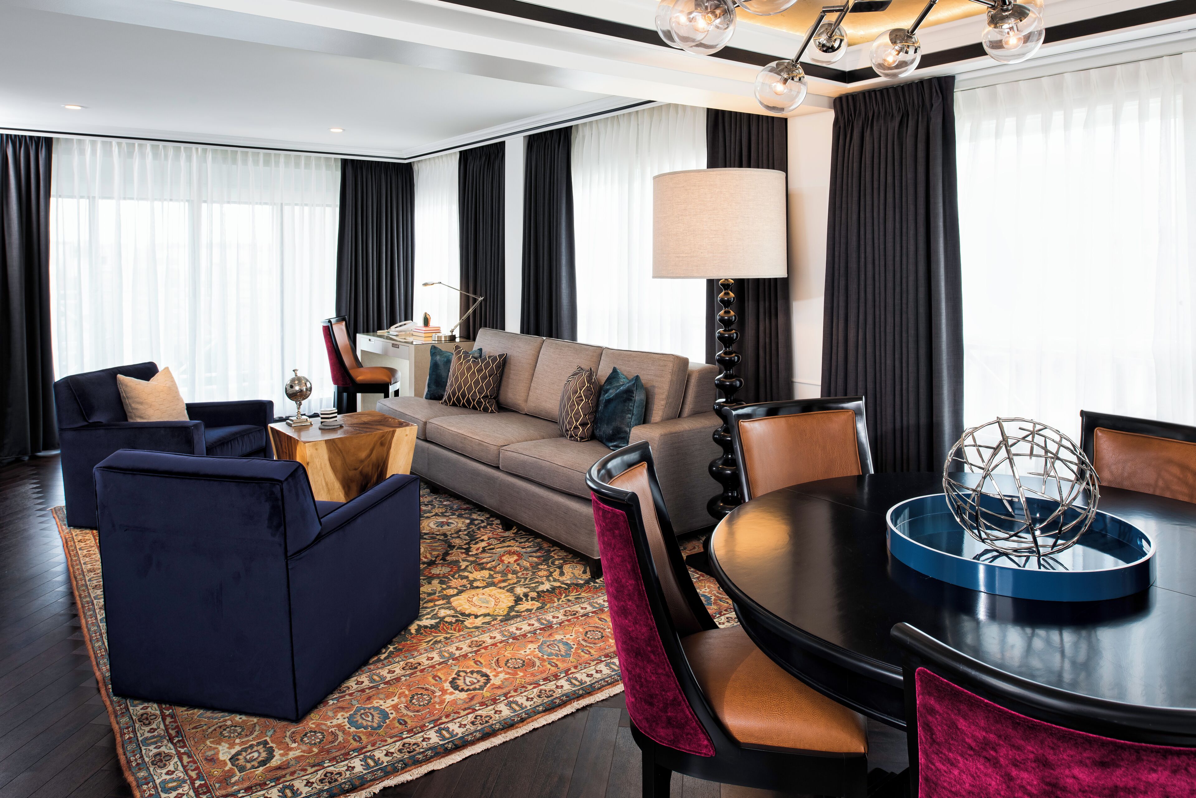 Een moderne woonkamer met een bank, stoelen, een eettafel en een lamp.
