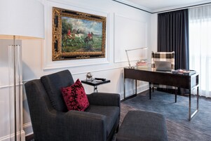 Une chambre moderne avec un canapé, un bureau, une lampe, une chaise et un tableau encadré au mur.
