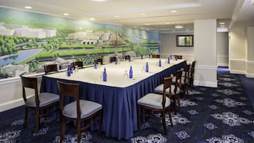 Un salón de conferencias con una gran mesa, sillas y un mural de un paisaje en la pared.