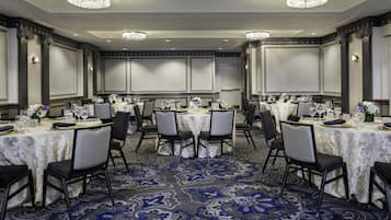 A conference room with round tables, chairs, and chandeliers.