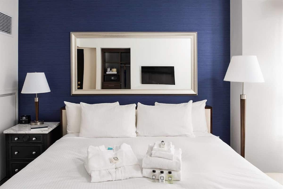 A hotel room with a large bed, two bedside tables, a mirror, and a TV.
