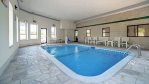 An indoor swimming pool with stone flooring, white walls, and a green stripe. There are chairs and a door with a sign. - Quality Inn Near Six Flags St. Louis (Pacific)