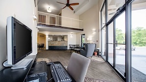 A modern hotel lobby with a computer desk, a flat-screen TV, and a ceiling fan. - Quality Inn Near Six Flags St. Louis (Pacific)