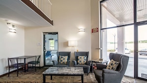 A lobby with a checkered carpet, a marble coffee table, two armchairs with patterned cushions, a sofa, and a dining table with chairs. - Quality Inn Near Six Flags St. Louis (Pacific)