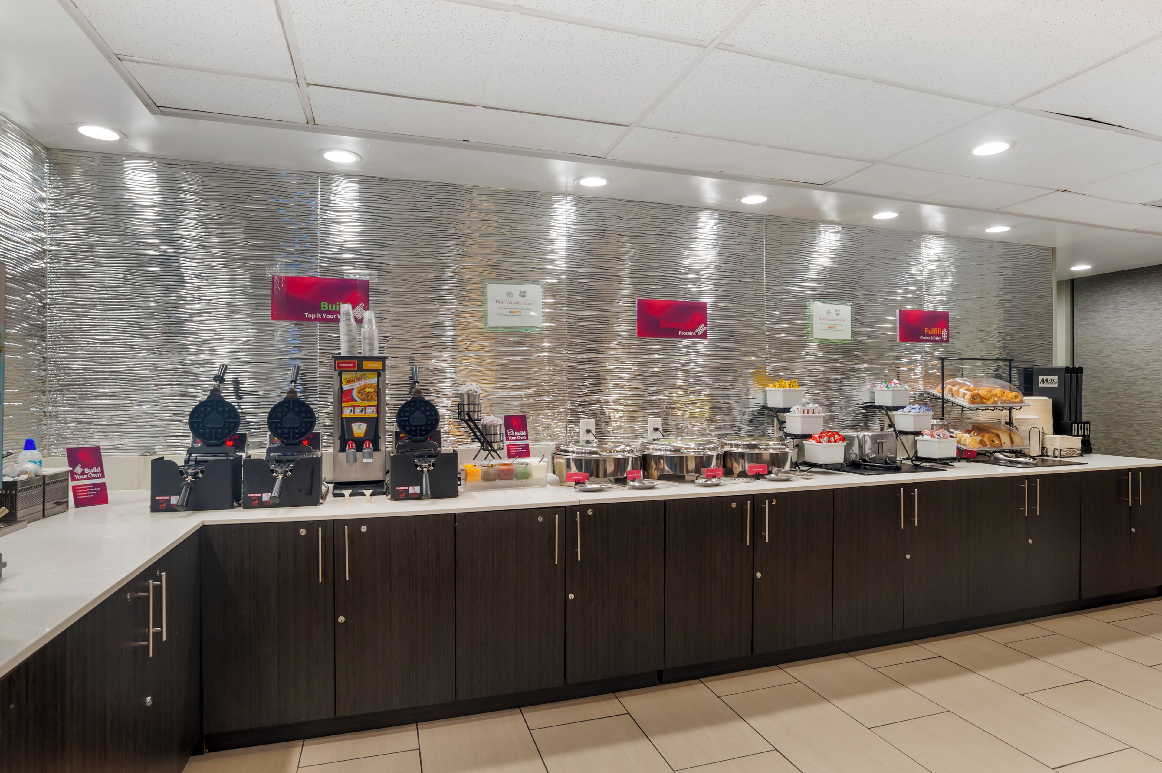 A buffet setup with various food stations, including a coffee machine, a fruit display, and a bread station.