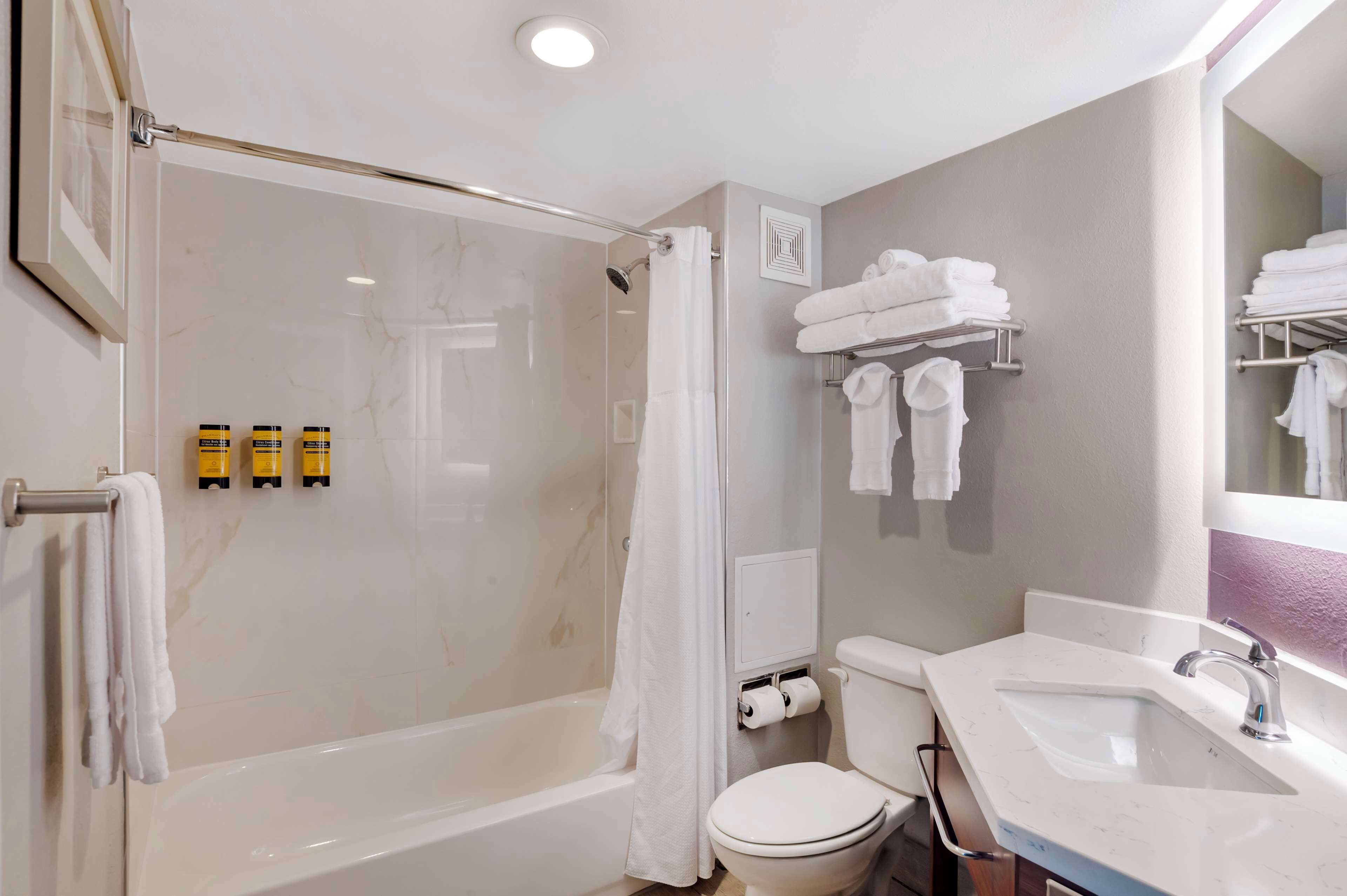A modern bathroom with a glass-enclosed shower, a white toilet, a sink, and a towel rack with neatly folded towels.