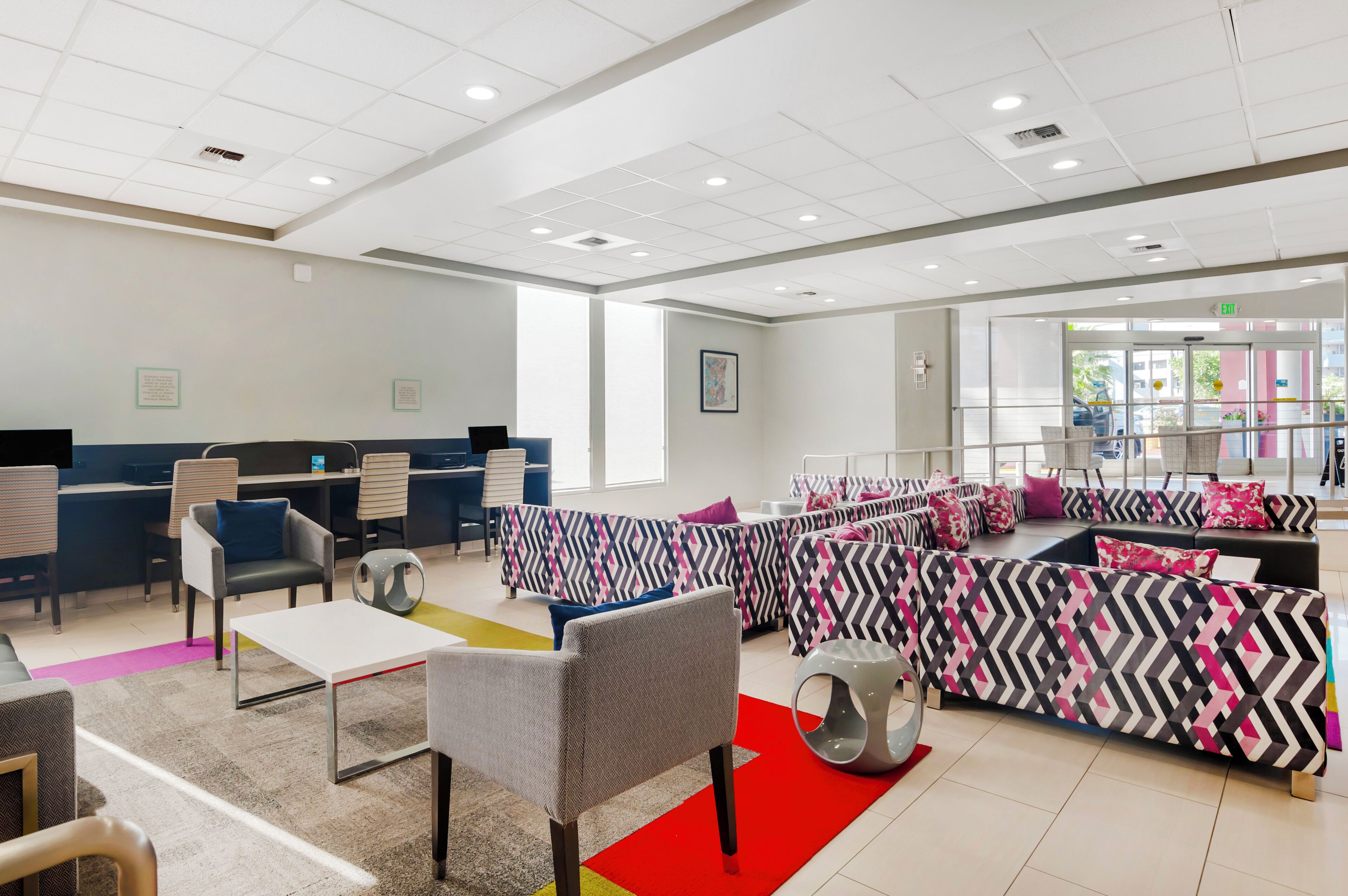 Et moderne kontormiljø med kontorpladser, et receptionområde og en lounge med møbler med et mønstret design.