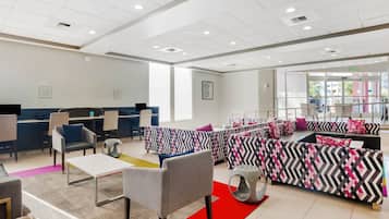 Et moderne kontormiljø med kontorpladser, et receptionområde og en lounge med møbler med et mønstret design.